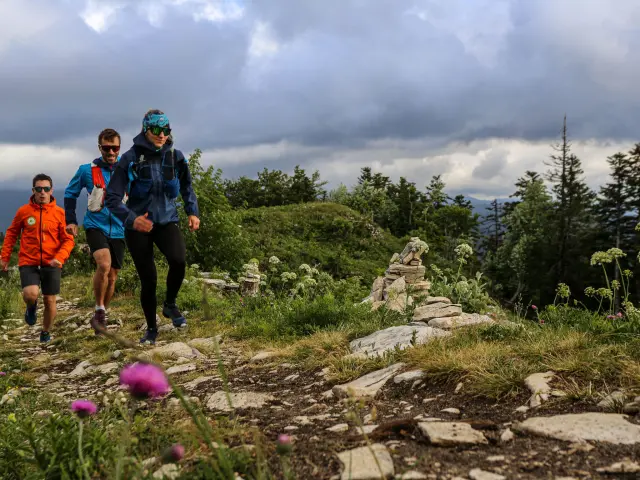 Quattro persone in escursione in montagna, con un cielo nuvoloso e rocce in primo piano