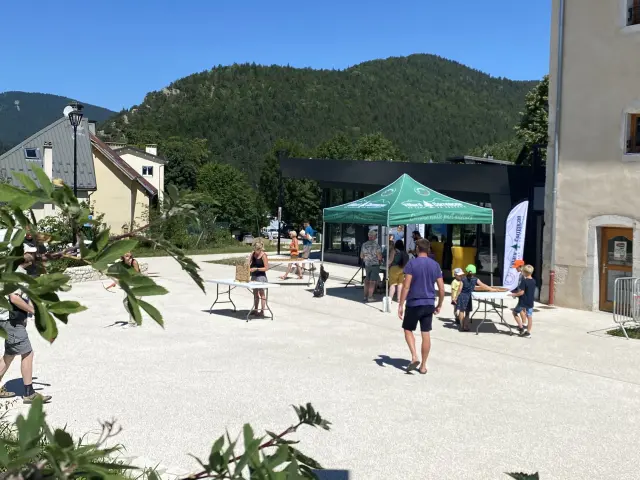 Terrazza di caffè in riva al porto con montagne sullo sfondo e passanti