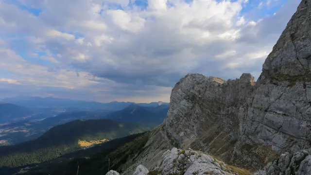 Vista di una cima rocciosa che domina una valle boschiva al tramonto