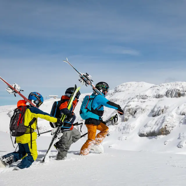 Trois skieurs en tenue de ski sur une piste enneigée avec des bâtons