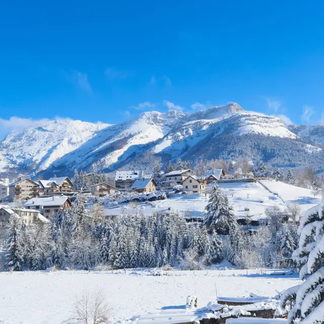 Villaggio di montagna innevato con baite e cime innevate sullo sfondo