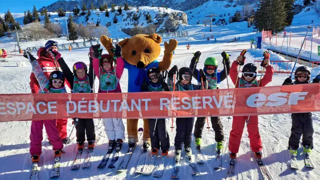 Gruppo di principianti dello sci su una pista con un istruttore, circondati da montagne innevate
