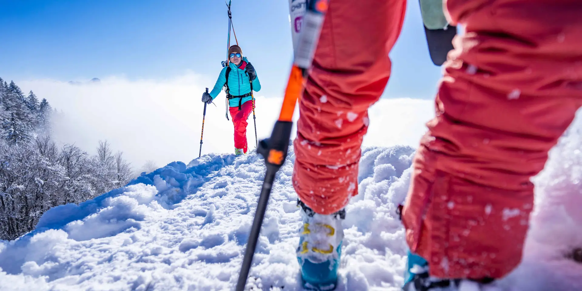 Deux skieurs en tenue rouge et bleu évoluent sur une piste de ski enneigée