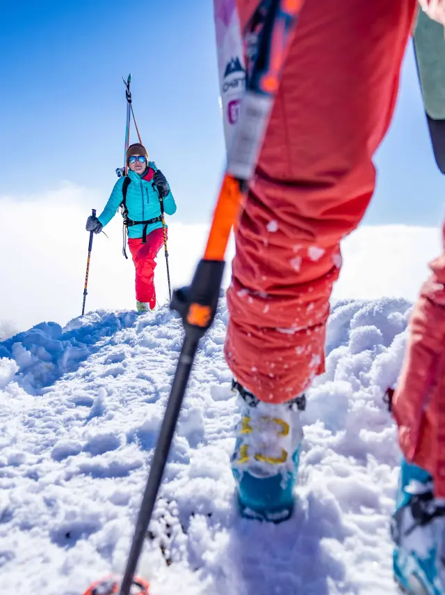 Due sciatori in tenuta rossa e blu si muovono su una pista da sci innevata