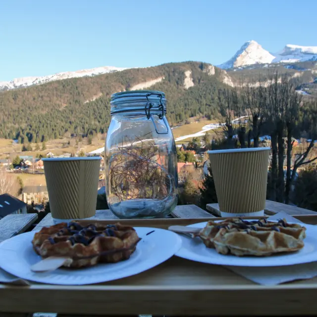 Due piatti di tapas e verdure grigliate su un tavolo in terrazza con vista su montagne innevate