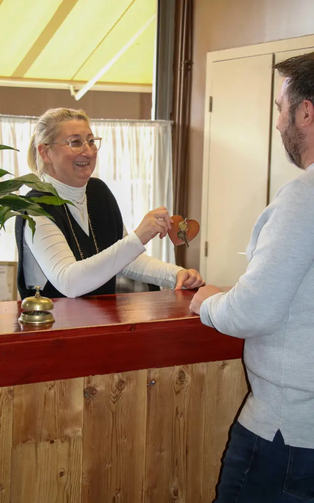 Due uomini, uno in completo e l'altro in camicia bianca, che parlano tenendo un bicchiere di vino