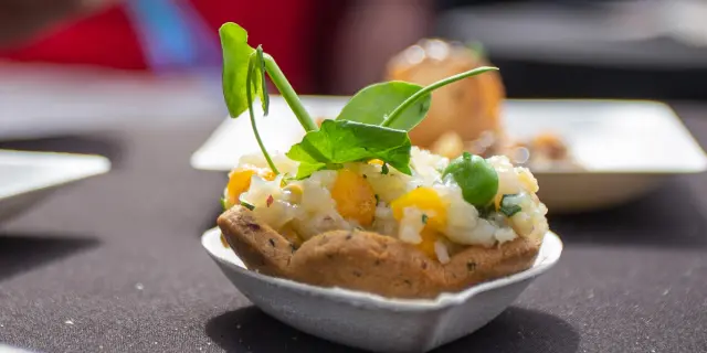 Tartare de saumon et avocat servi sur une tranche de pain grillé avec une feuille de basilic