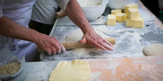 Personne découpant des cubes de fromage sur une planche en bois