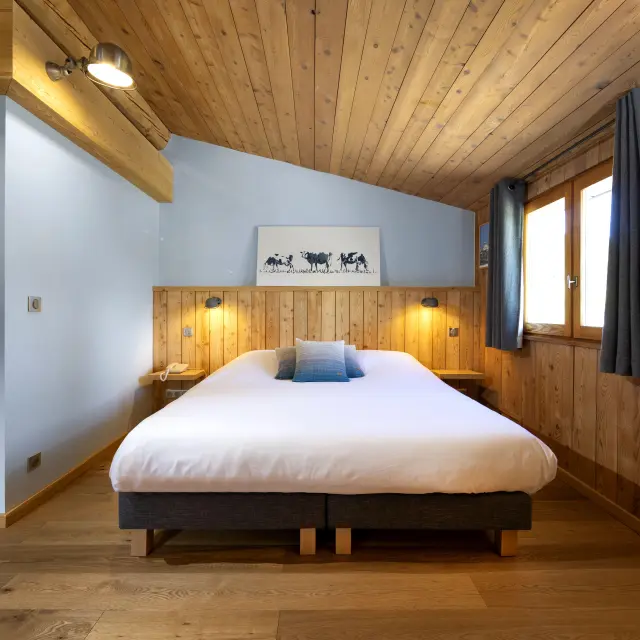 Chambre d'hôtel avec lit double, tête de lit en tissu et table de chevet