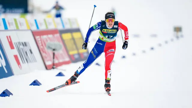 Ski alpiniste en combinaison bleue et rouge avec numéro 17, en descente sur une piste de ski balisée
