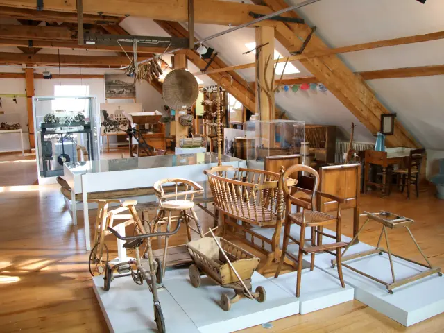 Sala di ristorante con tavoli in legno, sedie in vimini e bancone in legno chiaro