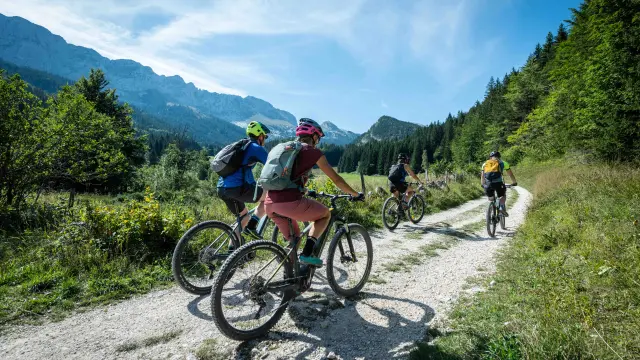 Deux cyclistes en montagne sur un sentier caillouteux avec des paysages de montagnes en arrière-plan