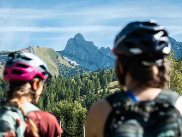 Deux personnes en randonnée en montagne, l'une avec un foulard rose et l'autre avec un casque audio