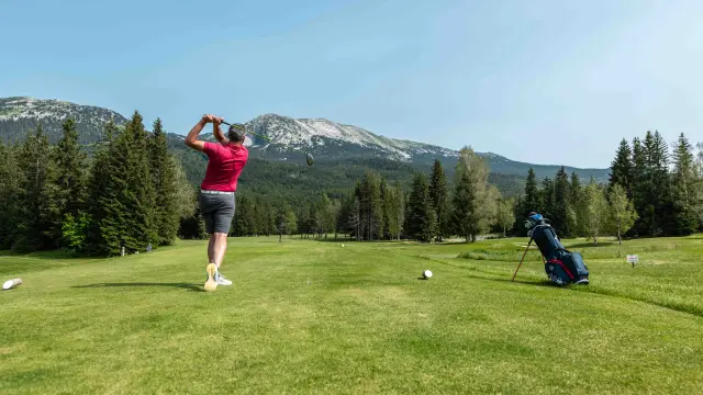 Deux joueurs s’affrontent en lançant un frisbee dans un parc herbeux entouré de montagnes