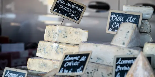 Formaggi stagionati su assi di legno con etichette che ne indicano il nome