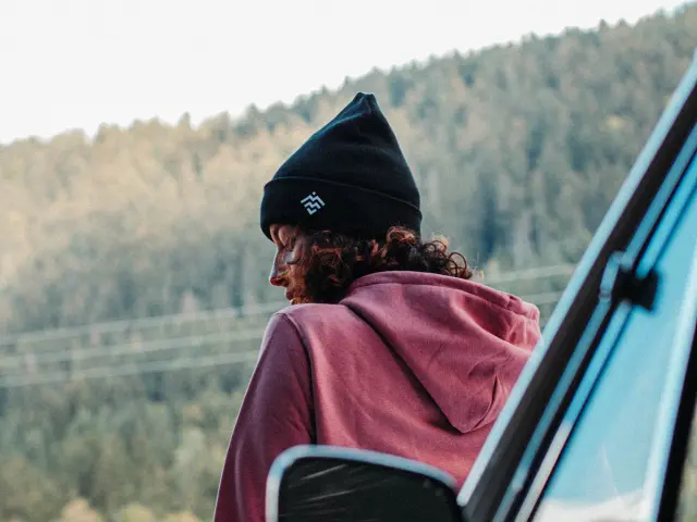 Donna seduta su una sedia a rotelle, vestita con una giacca rosa, che osserva un paesaggio con montagne sullo sfondo