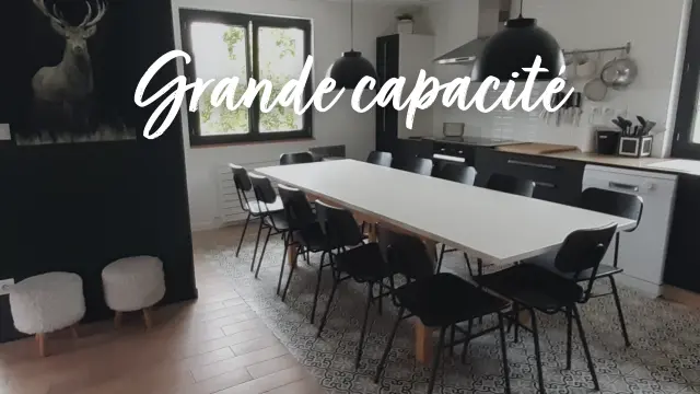 Aula riunioni con un grande tavolo bianco, sedie nere e uno schermo a parete con testo