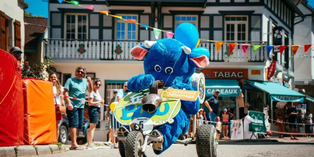 Dimostrazione di una moto elettrica blu con un pilota a bordo, davanti a edifici e passanti