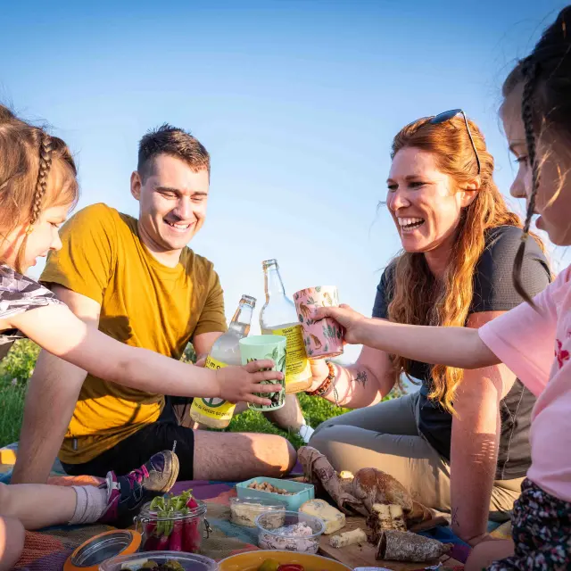 Quatre personnes attablées en terrasse, partageant des plats et des boissons