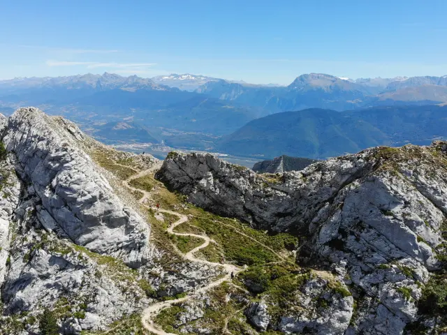 Vue d'un paysage montagneux avec des rochers escarpés et une vallée en contrebas au coucher du soleil
