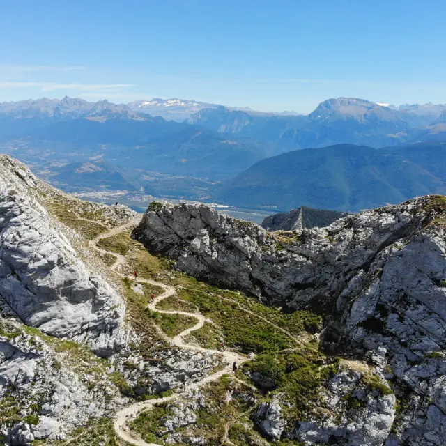 Vue d'un paysage montagneux avec des rochers escarpés et une vallée en contrebas au coucher du soleil