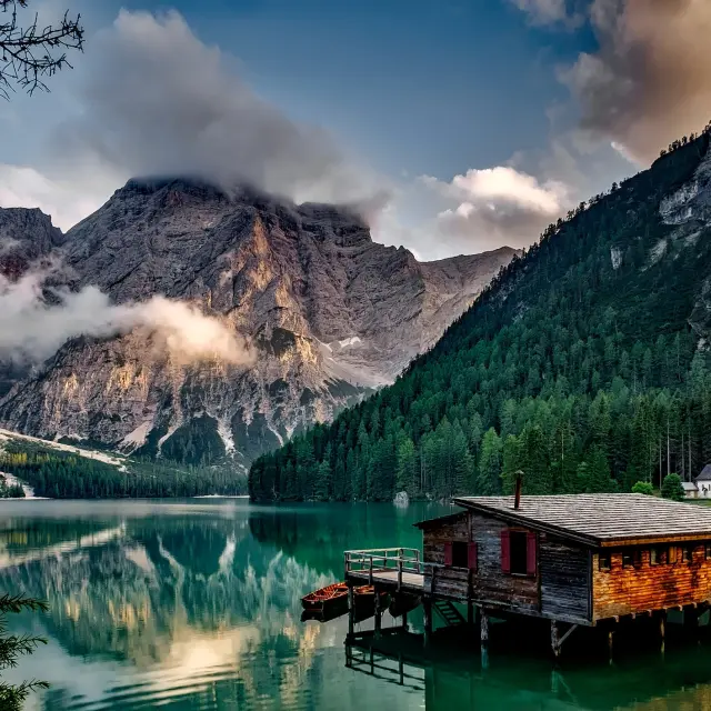 Port de montagne avec voiliers amarrés, bâtiments en bois et reflets sur l’eau au crépuscule