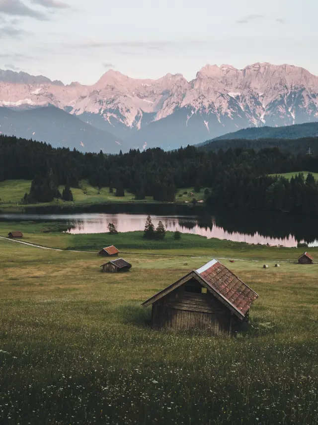 Paesaggio montano con barche a vela ormeggiate su un lago al tramonto