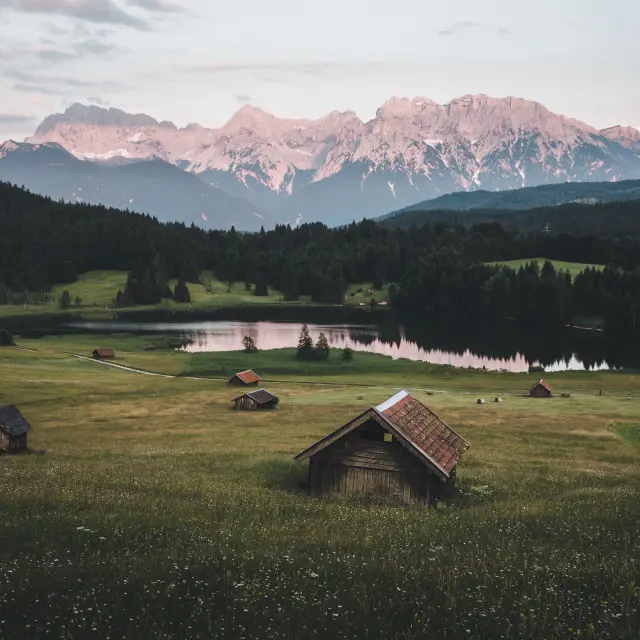 Paesaggio montano con barche a vela ormeggiate su un lago al tramonto