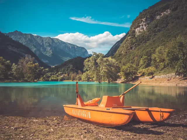 Due barche a vela arancioni ormeggiate vicino a un lago di montagna al tramonto