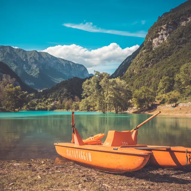 Due barche a vela arancioni ormeggiate vicino a un lago di montagna al tramonto