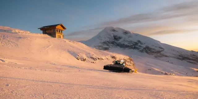 Petite cabane en bois sur une plage de sable rouge au coucher du soleil, avec des rochers en arrière-plan