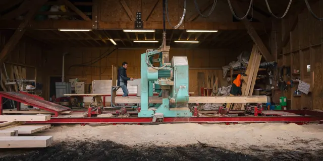 Atelier de réparation de voiliers avec des personnes travaillant sous une structure en bois