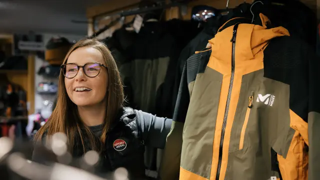 Donna con occhiali e badge che tiene una chitarra elettrica gialla in un negozio di musica