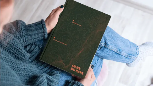 Trois livres empilés avec un carnet et un stylo posés sur un bureau en bois