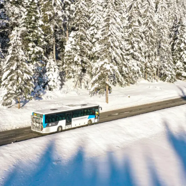 Téléphérique transportant des passagers au-dessus d'une vallée enneigée avec des montagnes en arrière-plan