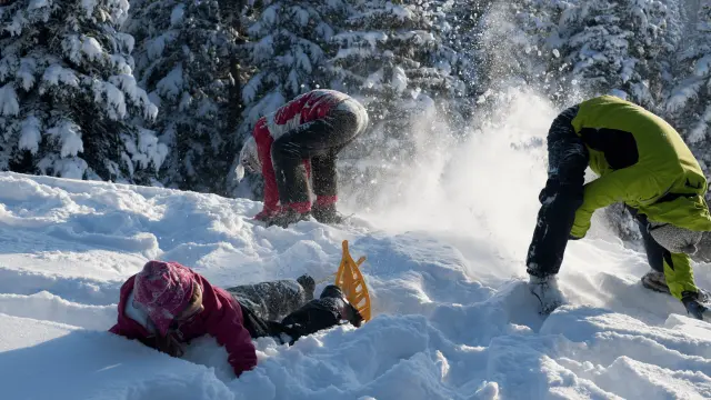 Due sciatori in tuta da sci rossa e verde che scendono una pista innevata con alberi sullo sfondo