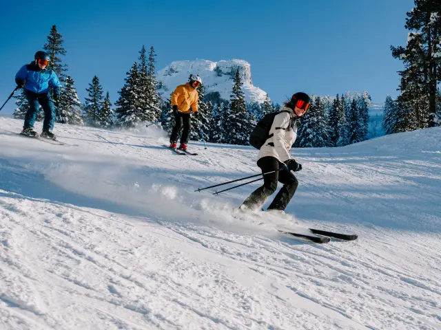 Deux enfants skiant sur une piste de ski avec des sapins enneigés en arrière-plan