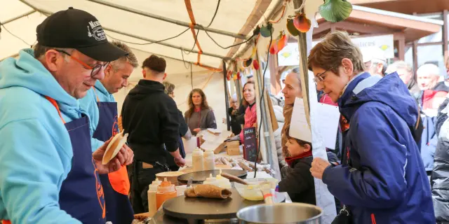 Stand de marché en plein air avec des artisans préparant des crêpes et des boissons