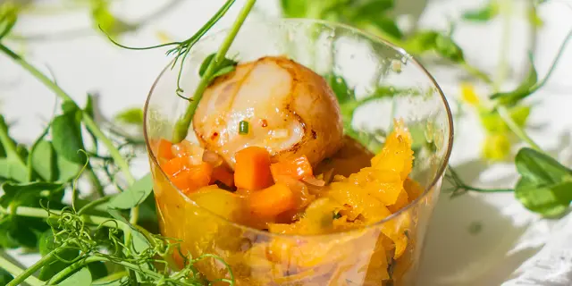 Tarte aux carottes et fromage frais sur une assiette en verre avec des feuilles de basilic