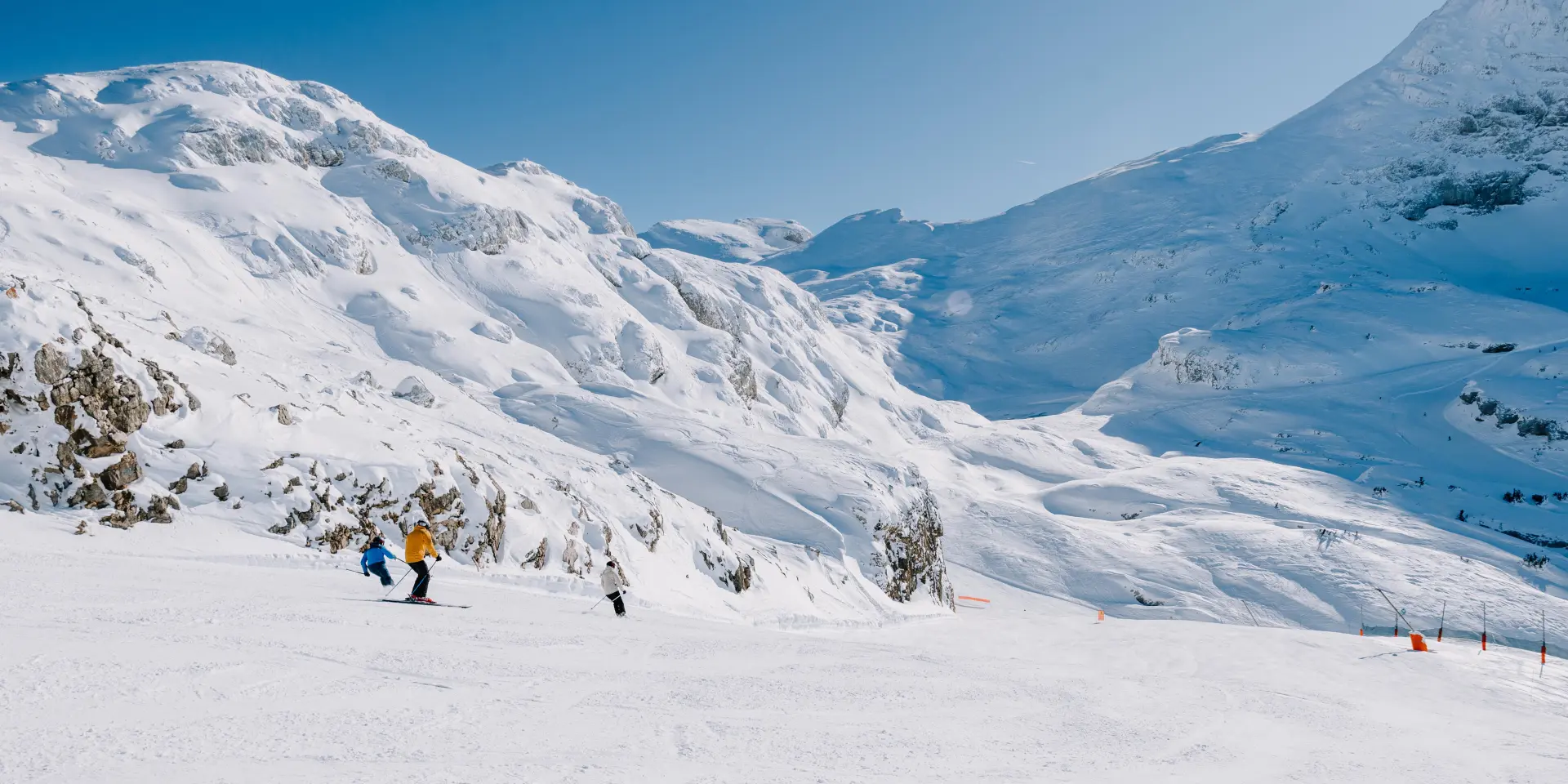 Gruppo di escursionisti con bastoncini e abbigliamento invernale che attraversano un paesaggio montuoso innevato