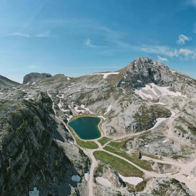 Vue d’une chaîne de montagnes enneigées descendant vers une côte rocheuse et une étendue d’eau bleue