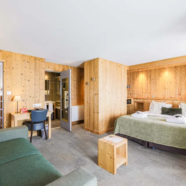 Camera d'albergo con letto matrimoniale, divano, tavolino e angolo scrivania