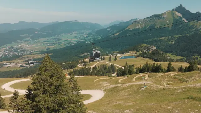 Route sinueuse en montagne avec des bâtiments et des voiliers amarrés dans une vallée