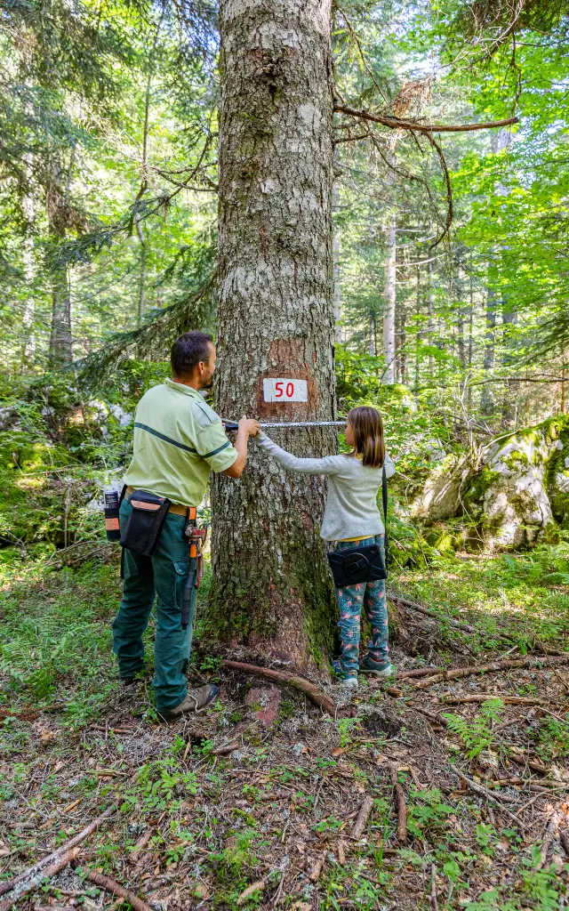 Deux personnes posant devant un arbre en forêt avec un panneau indicateur
