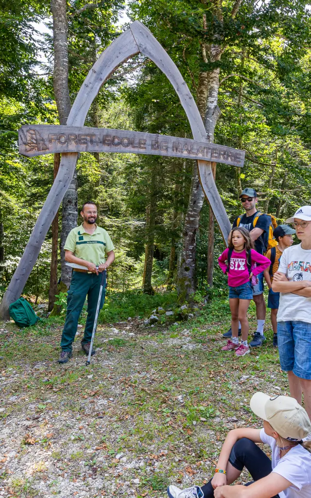 Enfants et adultes autour d’une cabane en bois dans une forêt