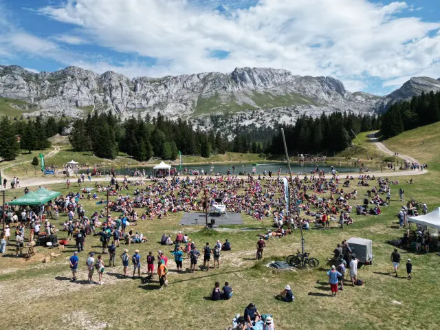 Grande assemblea di persone in un parco di montagna con montagne innevate sullo sfondo