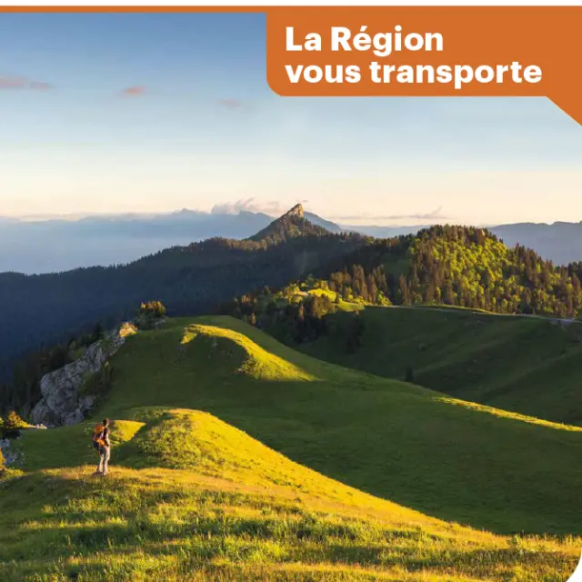 Paysage de montagne avec une route sinueuse, des panneaux directionnels vers Grenoble et des véhicules en arrière-plan