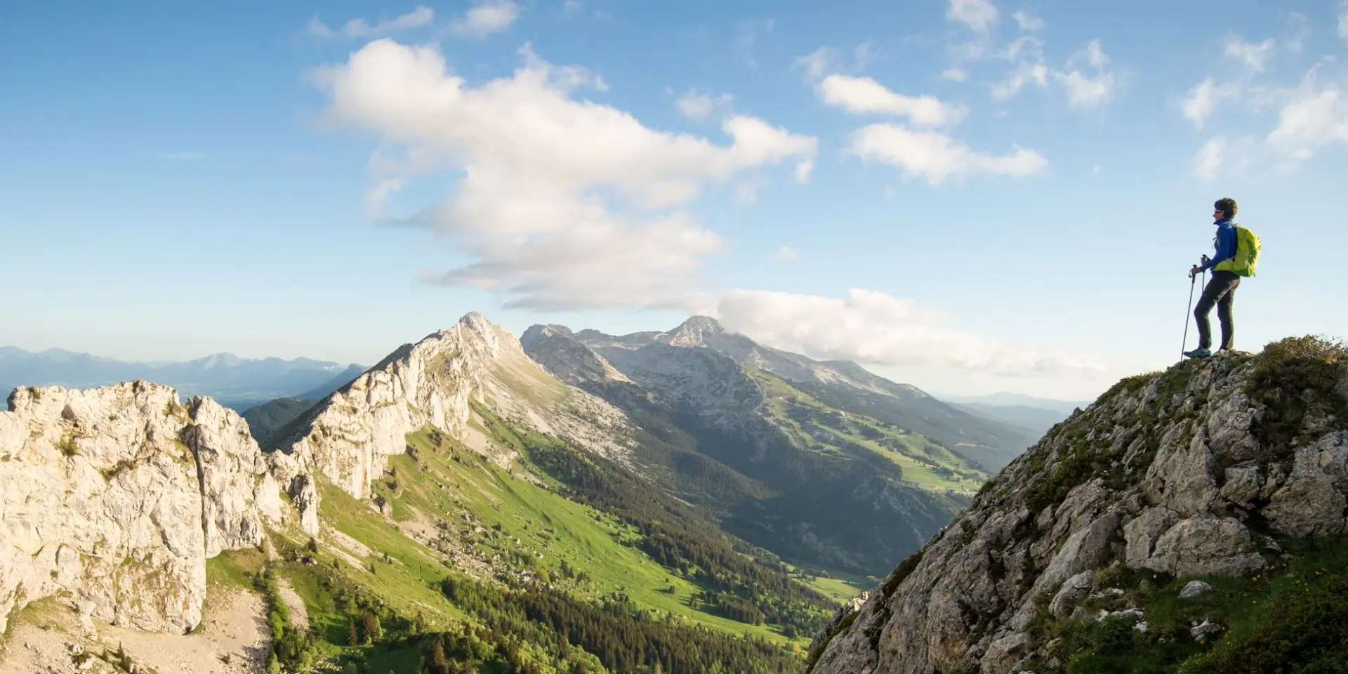 Escursionista in piedi su una roccia in montagna con vista su una valle