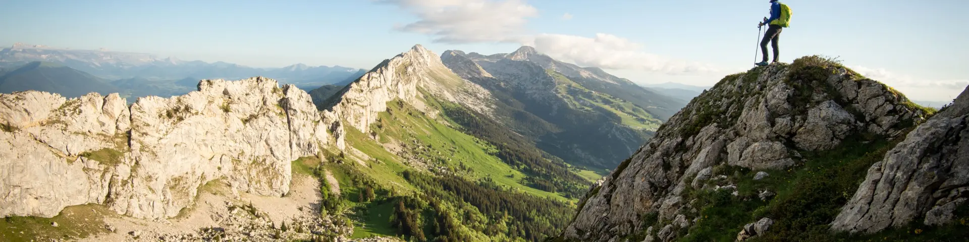 Escursionista in piedi su una roccia in montagna con vista su una valle