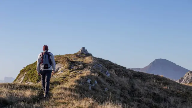 Deux randonneurs en tenue de montagne marchant sur une crête rocheuse avec des sommets enneigés en arrière-plan